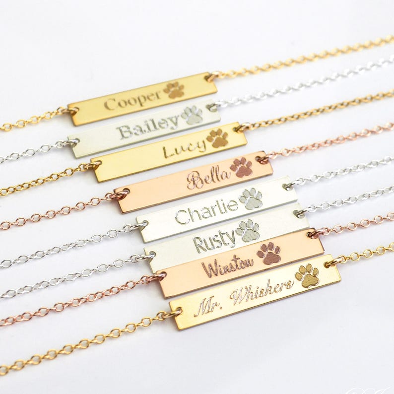Custom engraved dog name bar necklaces in gold, silver, and rose gold with paw print engraving, personalized pet jewelry for multiple pets, pet adoption keepsake bracelet or necklace, custom pet nameplate gifts for dog moms and cat lovers, layered name bar jewelry with pet names like Cooper, Bailey, and Rusty, thoughtful gift for new pet owners, animal rescue volunteers, or pet adoption day celebration, minimalist and meaningful pet lover jewelry handcrafted with love.