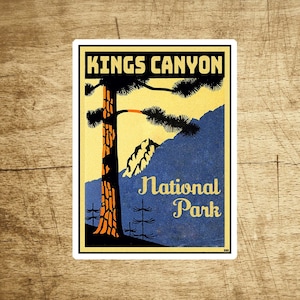 Op de afbeelding: Een vintage poster voor Kings Canyon National Park. De poster toont een hoge, oranje-bruine boom met een donkergroene kroon tegen een gele achtergrond. De tekst "Kings Canyon National Park" staat in zwarte letters bovenaan de poster. De tekst "National Park" staat in zwarte letters onderaan de poster.