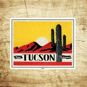 Puede incluir: Un cartel de viaje de estilo vintage con una ilustración roja, amarilla y negra de un paisaje desértico con un cactus y el texto "See Tucson Arizona".