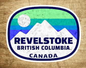 May include: A blue and white sticker with the text "Revelstoke, British Columbia, Canada" and a stylized mountain range with a sun in the background.