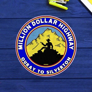 May include: A blue and yellow circular sign with the text "Million Dollar Highway Ouray to Silverton" and a silhouette of a person standing on a mountain.