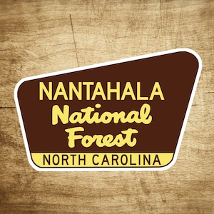 Puede incluir: Un letrero marrón y blanco con el texto "Nantahala National Forest" y "North Carolina" en letras amarillas.