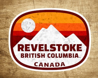 Könnte beinhalten: Ein weißer und roter Aufkleber im Vintage-Stil mit einer Bergkette und einer Sonne. Der Aufkleber lautet "Revelstoke British Columbia Canada".