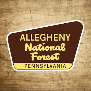 Könnte beinhalten: Ein braunes und gelbes Schild mit weißem Rand, in Form eines spitzen Pfeils, lautet "ALLEGHENY National Forest PENNSYLVANIA".