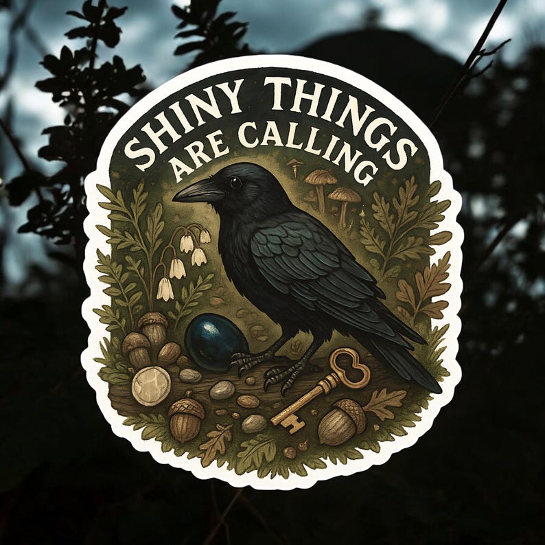 Puede incluir: Pegatina redonda con un cuervo negro y el texto "SHINY THINGS ARE CALLING". El cuervo est&aacute; rodeado de bellotas, una llave y elementos naturales. La pegatina tiene un borde blanco sobre un fondo oscuro.