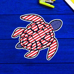 May include: A red, white, and blue sea turtle with an American flag design. The turtle is on a blue wooden background.