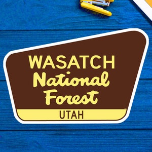 May include: A brown and yellow sign with the text "Wasatch National Forest Utah" in a retro style font.