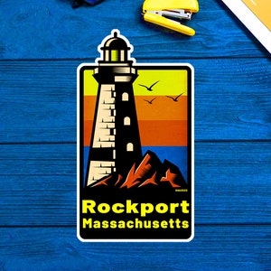 May include: A sticker featuring a black and white illustration of a lighthouse with a yellow, orange, and blue sunset background. The text "Rockport Massachusetts" is printed in black below the lighthouse.