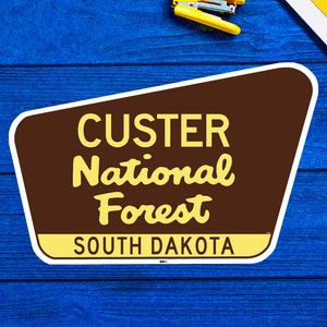 Peut inclure: Un panneau brun et jaune avec le texte "CUSTER National Forest SOUTH DAKOTA".