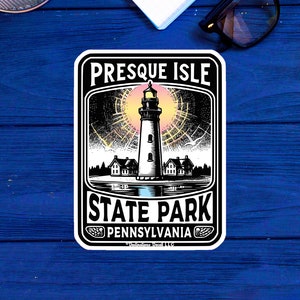 May include: A black and white illustration of a lighthouse with a pink and yellow sunset behind it. The text "Presque Isle State Park Pennsylvania" is below the lighthouse.