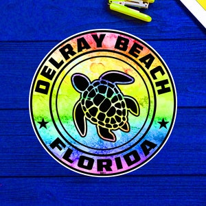 May include: A rainbow-colored circle sticker with the text "Delray Beach Florida" and a black silhouette of a sea turtle in the center.