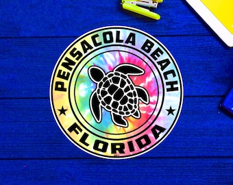 May include: A round sticker with a tie-dye background and a black sea turtle silhouette. The sticker says "Pensacola Beach Florida" in a white circle around the turtle.
