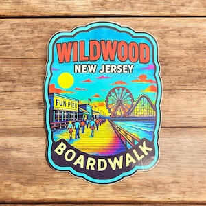 May include: A colorful Wildwood New Jersey Boardwalk sticker. The sticker features a boardwalk scene with a Ferris wheel, roller coaster, and people walking. The text "Wildwood New Jersey Boardwalk" is displayed in red and white.