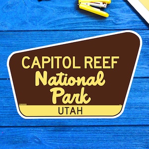 May include: A brown and yellow sign with the text "CAPITOL REEF National Park UTAH".