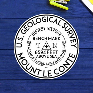 May include: A white round sticker with black text that reads "U.S. Geological Survey Mount Le Conte Great Smoky Mountains National Park Do Not Disturb Bench Mark T A N 6594 Feet Above Sea 000"