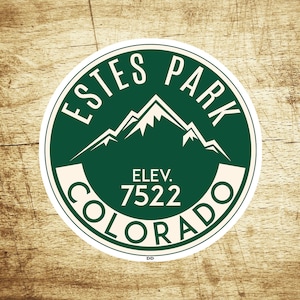 May include: A green and white circular sticker with the text "ESTES PARK COLORADO" and "ELEV. 7522" inside. The sticker features a stylized mountain range.