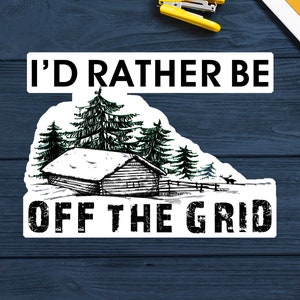 May include: White sticker with black text that reads "I'd rather be off the grid". The sticker features a black and white illustration of a cabin in the woods with snow on the roof.