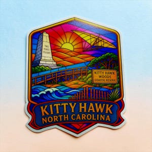 May include: A colorful sticker featuring a stained-glass style illustration of Kitty Hawk, North Carolina. It depicts the Wright Brothers National Memorial with the text The First Flight, a hang glider, a wooden boardwalk, and a Kitty Hawk Woods Coastal Reserve sign.