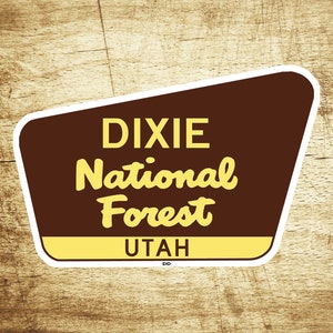 May include: A brown and white vintage-style sign with the text "Dixie National Forest Utah" in yellow lettering.