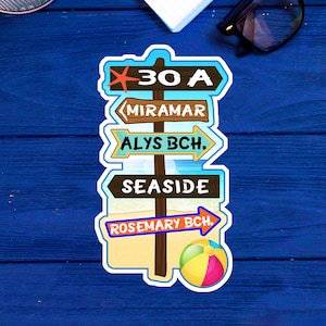 May include: A colorful sticker featuring a beach-themed signpost with arrows pointing to various destinations: 30 A, Miramar, Alys Bch., Seaside, and Rosemary Bch. A beach ball is also included in the design.