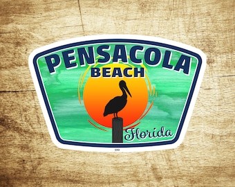 May include: A blue and white sticker with the text "Pensacola Beach Florida" and a silhouette of a pelican standing on a post in front of a sunset.