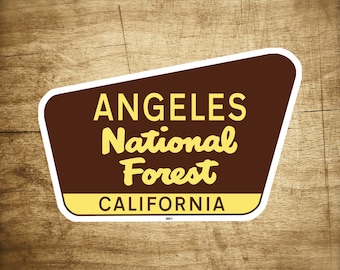 Puede incluir: Un letrero marrón y amarillo con borde blanco que dice "Angeles National Forest, California".