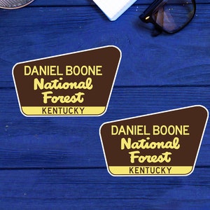 May include: Two brown and yellow stickers with rounded corners. The stickers feature the text "Daniel Boone National Forest" and "Kentucky".