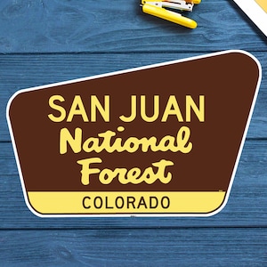 May include: A brown and yellow sign with the text "SAN JUAN National Forest COLORADO".