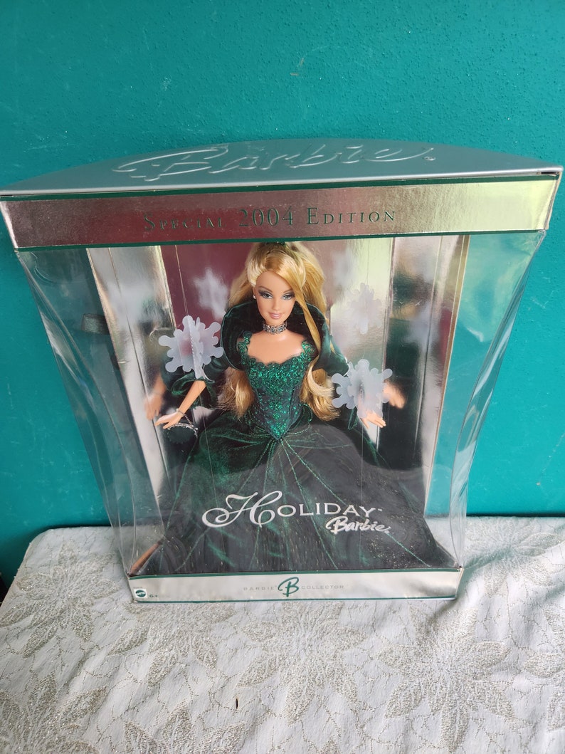 May include: 2004 Holiday Barbie Special Edition doll in a clear plastic display box. The doll wears a dark green velvet gown with a sparkly bodice. The box features silver accents and the text 'Barbie Special 2004 Edition' and 'Holiday Barbie'.