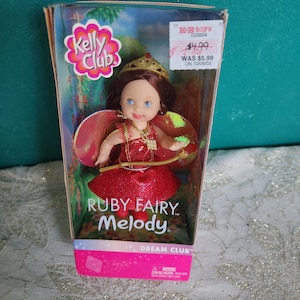 May include: A red and pink doll box featuring a doll with red wings and a red dress. The doll is holding a wand. The box says "Ruby Fairy Melody" and "Dream Club".