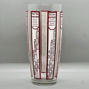 Peut inclure: Un shaker &agrave; cocktail en verre transparent avec des marques rouges et blanches. Le shaker comporte des mesures pour faire un Martini et un Bronx. Les mesures sont en onces. Le texte sur le shaker indique "Martini" et "Bronx".