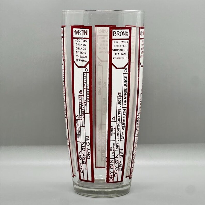 Peut inclure: Un shaker &agrave; cocktail en verre transparent avec des marques rouges et blanches. Le shaker comporte des mesures pour faire un Martini et un Bronx. Les mesures sont en onces. Le texte sur le shaker indique "Martini" et "Bronx".