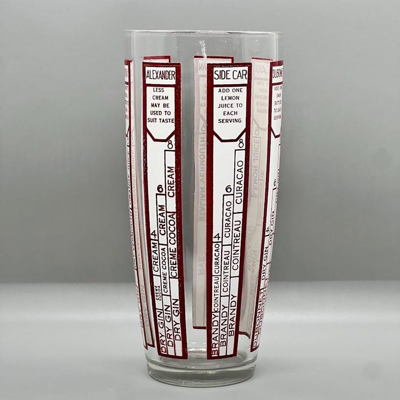 Peut inclure: Un shaker &agrave; cocktail en verre transparent avec des marques rouges et blanches. Les marques comprennent les noms des cocktails et la quantit&eacute; de chaque ingr&eacute;dient n&eacute;cessaire. Les cocktails list&eacute;s sont Alexander, Side Car et Dubonnet.