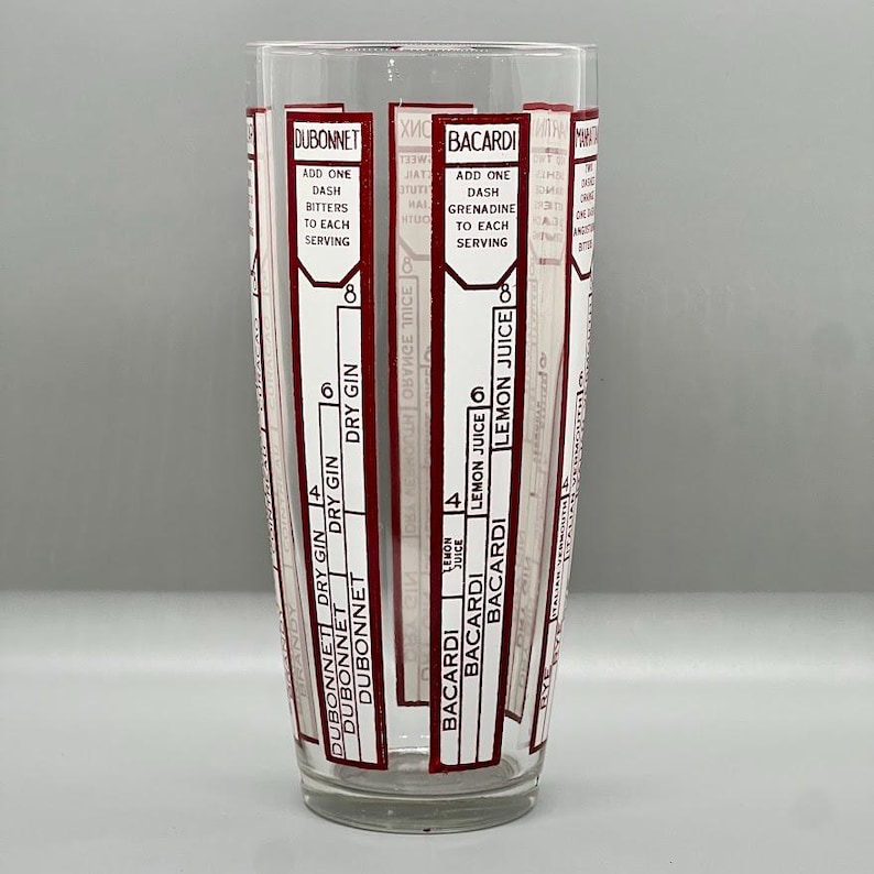Peut inclure: Un shaker &agrave; cocktail en verre transparent avec des &eacute;tiquettes rouges et blanches pour la pr&eacute;paration de cocktails. Les &eacute;tiquettes comprennent les marques Dubonnet et Bacardi, ainsi que des instructions pour ajouter des ingr&eacute;dients tels que du gin sec, du jus de citron et de la grenadine.