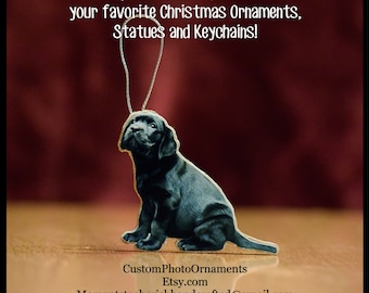 May include: A black Labrador Retriever puppy ornament with a silver string for hanging. The ornament is in a sitting position, looking upwards. Text on the image reads: "Turn your favorite photos into your favorite Christmas Ornaments, Statues and Keychains!"