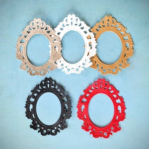 May include: An assortment of five ornate oval picture frames in various colors: beige, white, gold, black, and red. The frames have a detailed, decorative design around the oval opening, set against a light blue background.