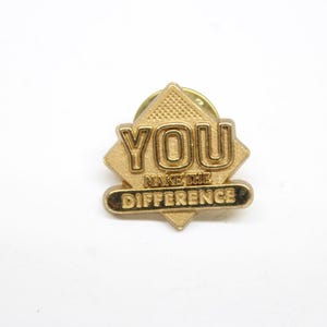 May include: Gold-colored pin with the words "YOU MAKE THE DIFFERENCE" in a diamond shape.