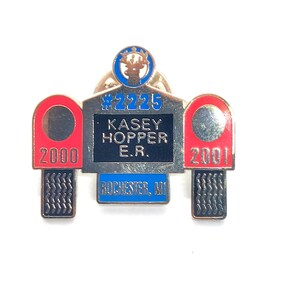 May include: A vintage pin with a deer emblem at the top. The pin features the text "#2225", "Kasey Hopper E.R.", and "Rochester, MI". Red and silver accents with the numbers "2000" and "2001" are on either side.