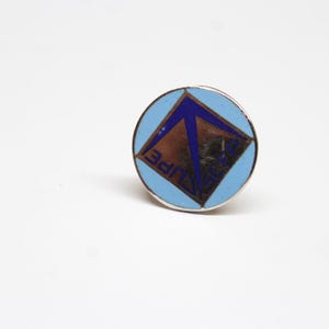 May include: A blue and silver pin with a blue triangle and the word "ECLIPSE" in white letters.