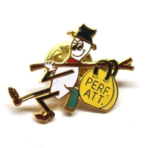 May include: Gold-tone pin featuring a cartoon snowman holding a yellow bag with the text "PERF. ATT." The snowman is wearing a black hat and green pants.