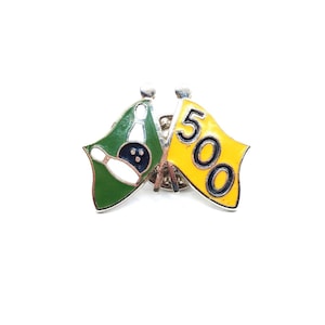 May include: A bowling pin with a bowling ball on a green flag and a yellow flag with the number 500. The pin is white, the ball is blue, and the flags are on silver posts.