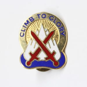 May include: A gold-colored pin with the words "CLIMB TO GLORY" in blue lettering. The pin features two crossed red swords over a white mountain range design, set against a gold sunburst background.