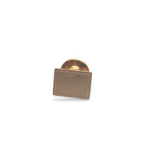 May include: A gold-toned cufflink with a square-shaped face.