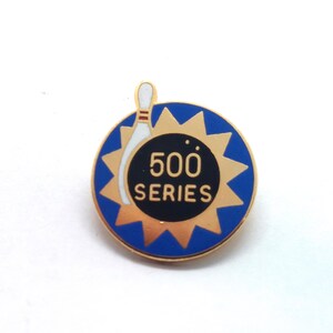 May include: A round pin with a blue and gold design. The pin features a bowling pin graphic and the text "500 SERIES" in white. The pin has a gold border and a blue background with gold starburst accents.