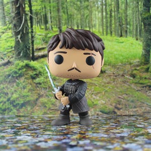 May include: A vinyl collectible figure featuring a character with brown hair, a thin mustache, and a small scar above the left eye. The figure wears a dark gray quilted tunic and holds a silver sword with a green-tinted blade in the right hand.