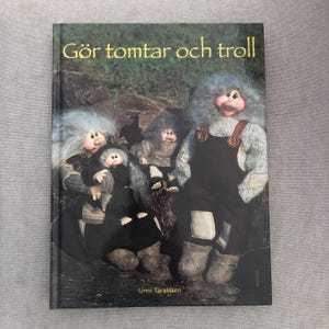 May include: A book cover featuring the title "Gör tomtar och troll" with illustrations of troll-like figures. The figures have gray, fluffy hair and are wearing dark overalls. The author's name, Unni Taraldsen, is at the bottom.