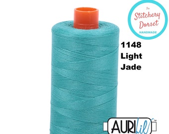 May include: A spool of teal blue Aurifil thread with the number 1148 and the words "Light Jade" printed on the label. The label also includes the words "The Stitchery Dorset Handmade".