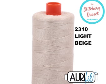May include: A spool of Aurifil thread in the color 2310 Light Beige. The spool is labeled "The Stitchery Dorset Handmade".