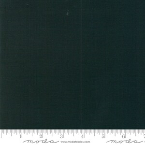 May include: A solid dark green fabric swatch with a ruler showing 7 inches. The ruler has the word "moda" written on it in cursive.