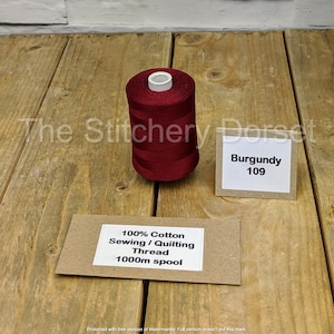 May include: A 1000m spool of burgundy sewing and quilting thread made from 100% cotton. The spool is labelled "Burgundy 109" and "100% Cotton Sewing / Quilting Thread 1000m spool".